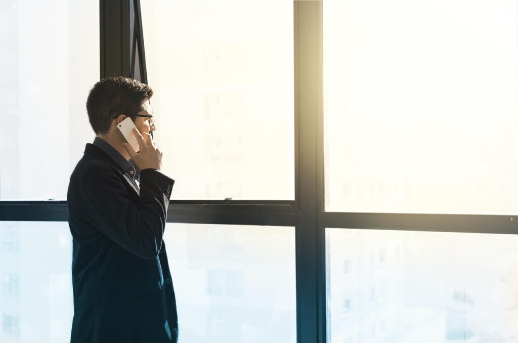 Entrepreneur devant une fenêtre entrain de parler au téléphone